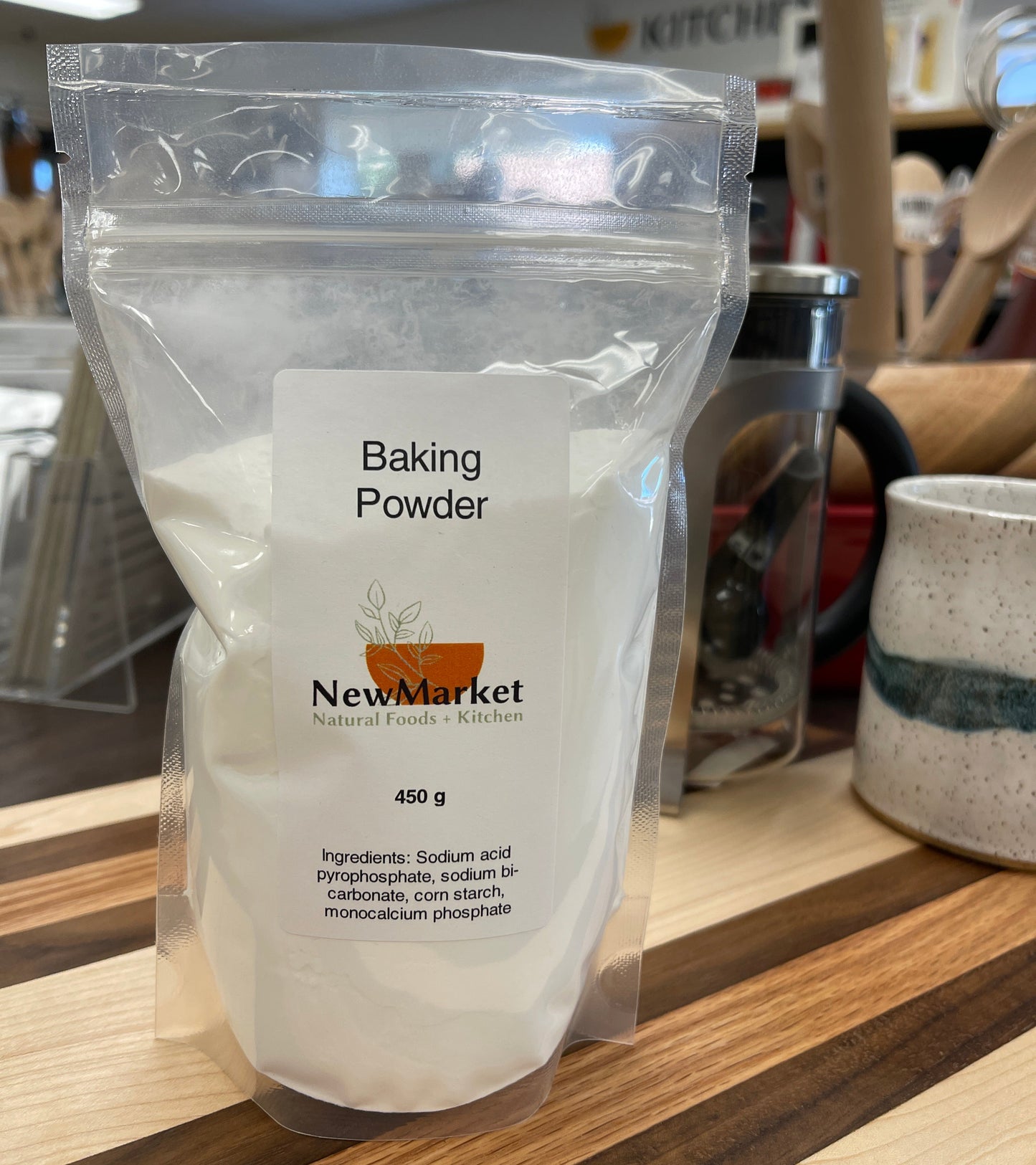 Resealable bag of baking powder, 450g. Sitting on a wood cutting board.