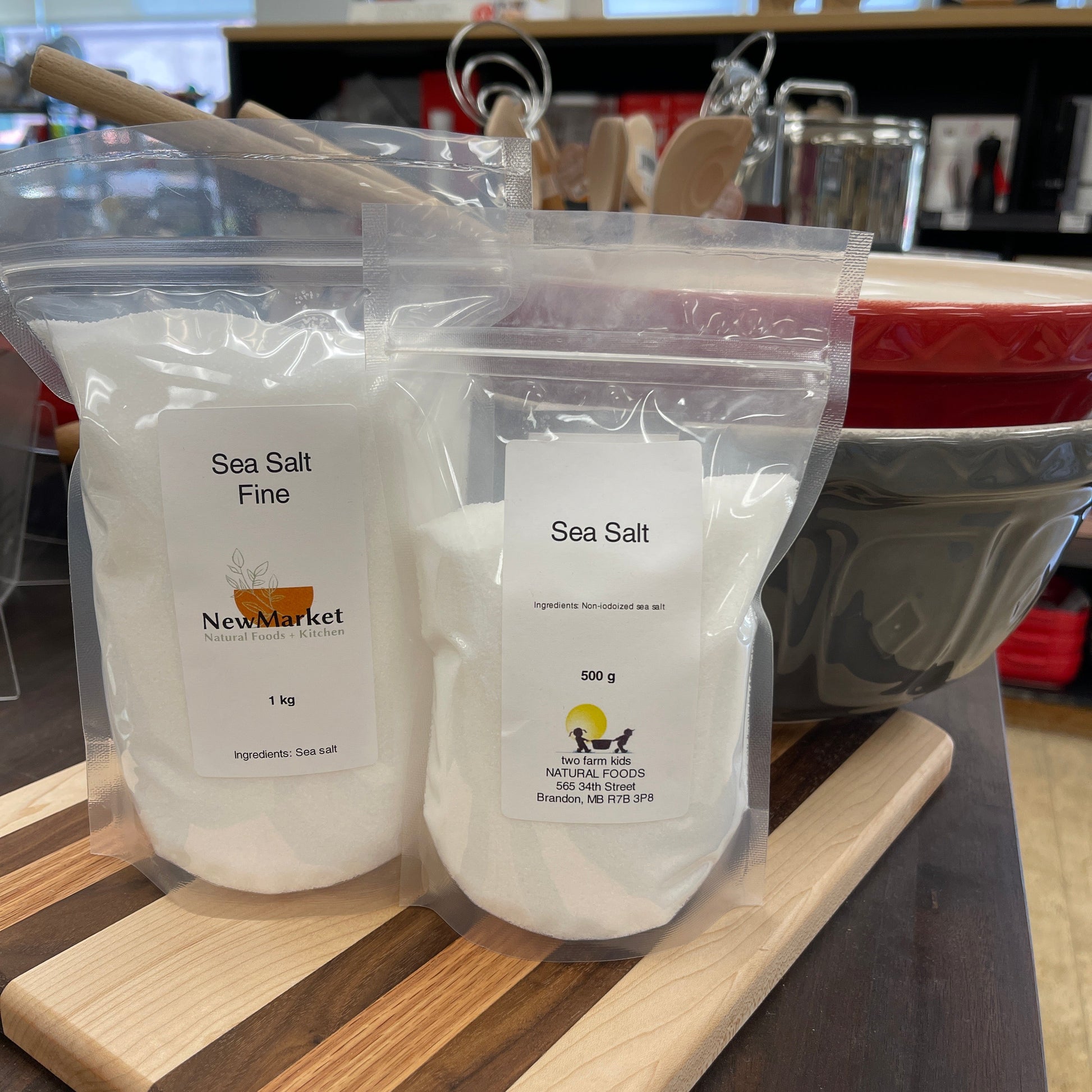 Two containers of sea salt on a wooden surface with a blurred background
