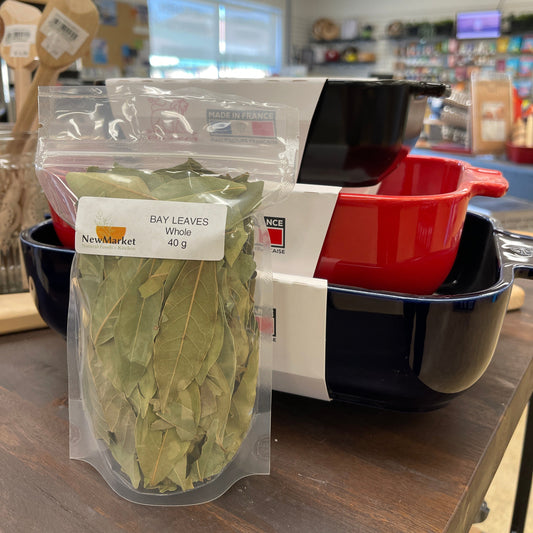 Plastic bag of whole bay leaves on a table with dishes in the background.