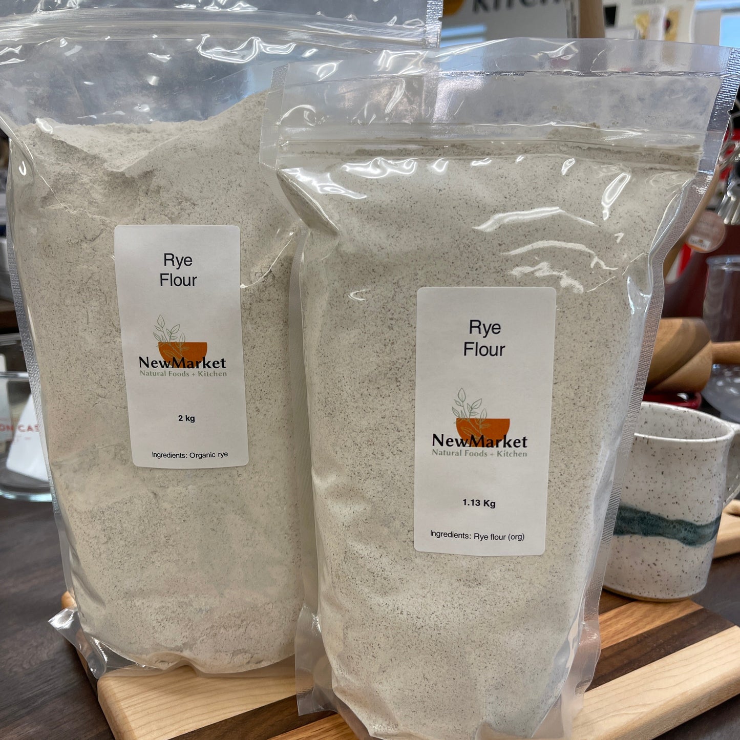 Two packages of rye flour with New Market label on a wooden surface