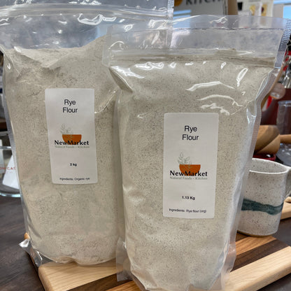 Two packages of rye flour with New Market label on a wooden surface