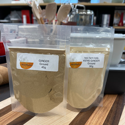 Two packages of ginger root with labels on a wooden surface.