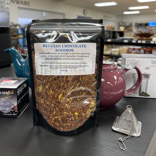 Package of belgian chocolate rooibos tea with tea pots and tea diffuser.