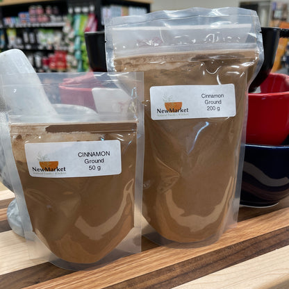 Two packages of cinnamon powder on a wooden surface with a blurred store background.