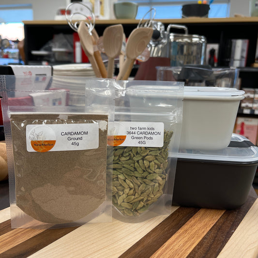 Two packages of cardamon spice on a cutting board.