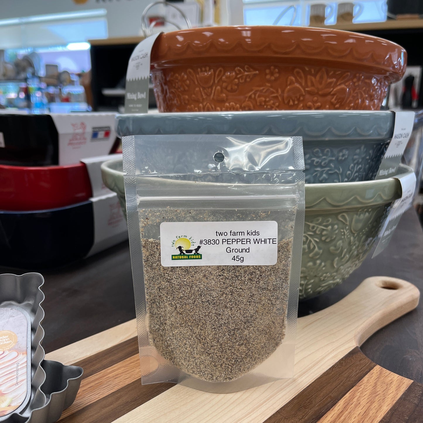 Package of ground white pepper sitting on cutting board.