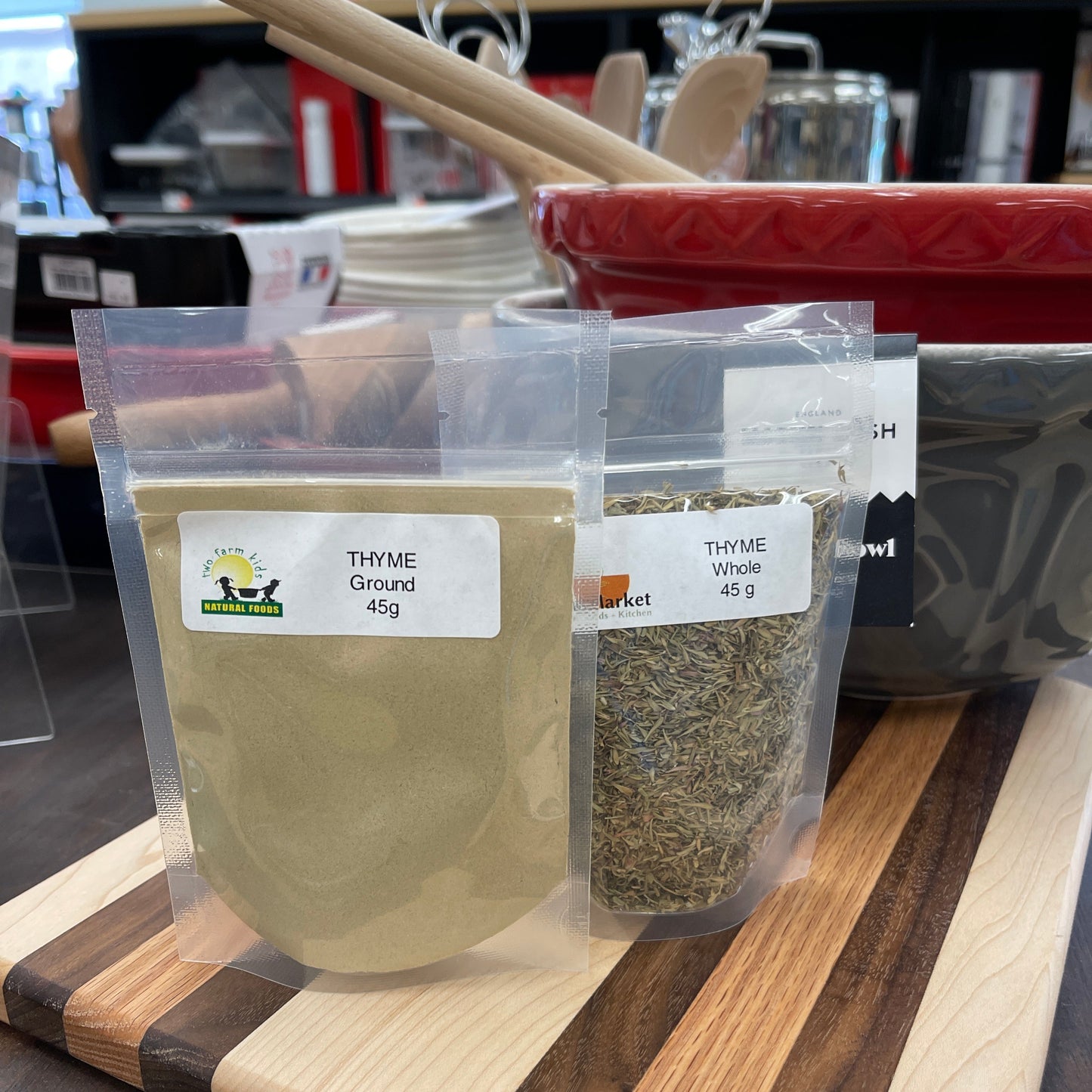 Packaged thyme ground and whole on a wooden cutting board with a blurred background