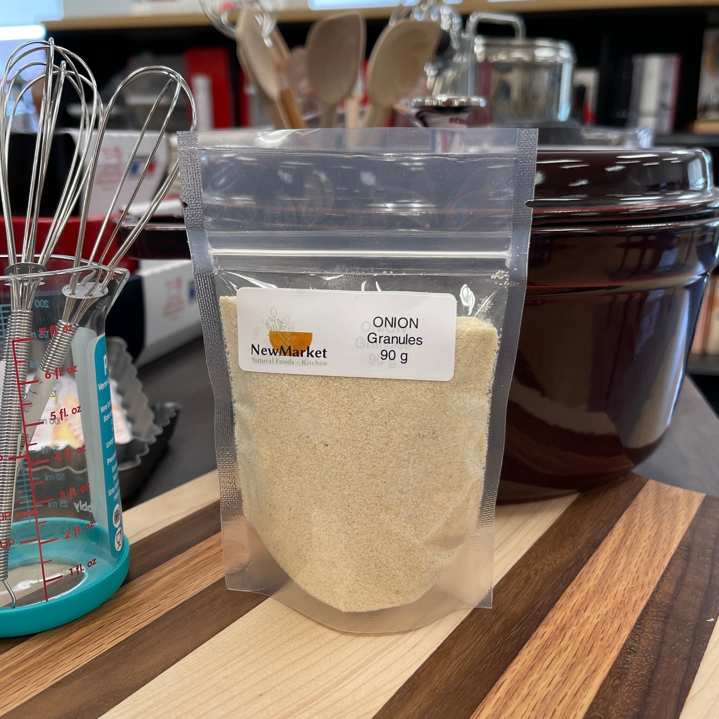 Packaged onion granules on a kitchen shelf with utensils and containers in the background