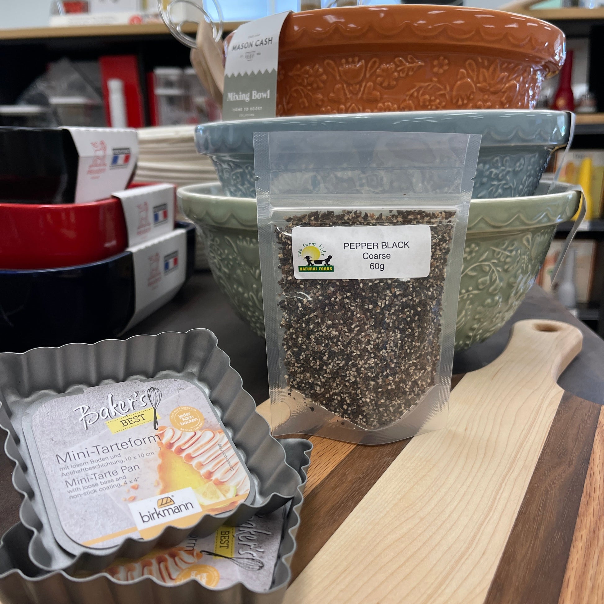 Package of coarse black pepper, 60g, on cutting board next to bowls.