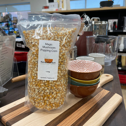 Bag of magic mushroom popcorn kernels on a kitchen counter with cutting boards and kitchen tools in the background.
